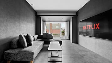 A modern living room with a sectional sofa, a coffee table, and a large window with a view of buildings.