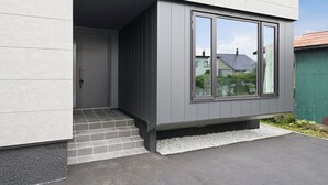A modern building with a grey exterior, a large window, and a small entrance with steps. - HT-I (Asahikawa)