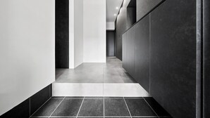 A modern hallway with a straight path, dark walls, and a tiled floor. - HT-I (Asahikawa)