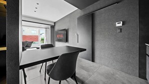 A modern interior with a conference table, chairs, a mounted TV, and a thermostat on the wall. - HT-I (Asahikawa)