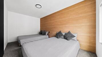 A modern hotel room with two beds, a wooden accent wall, and a simple, clean design.
