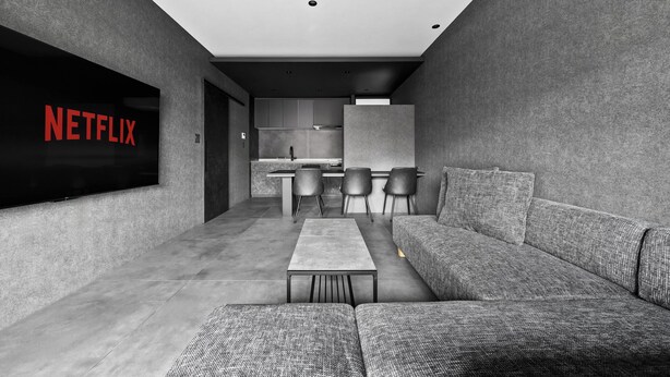 A modern living room with a sectional sofa, a flat-screen TV, and a minimalist design. - HT-I (Asahikawa)