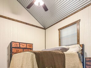 Un dormitorio con cama, cómoda, ventana con persianas y ventilador de techo.