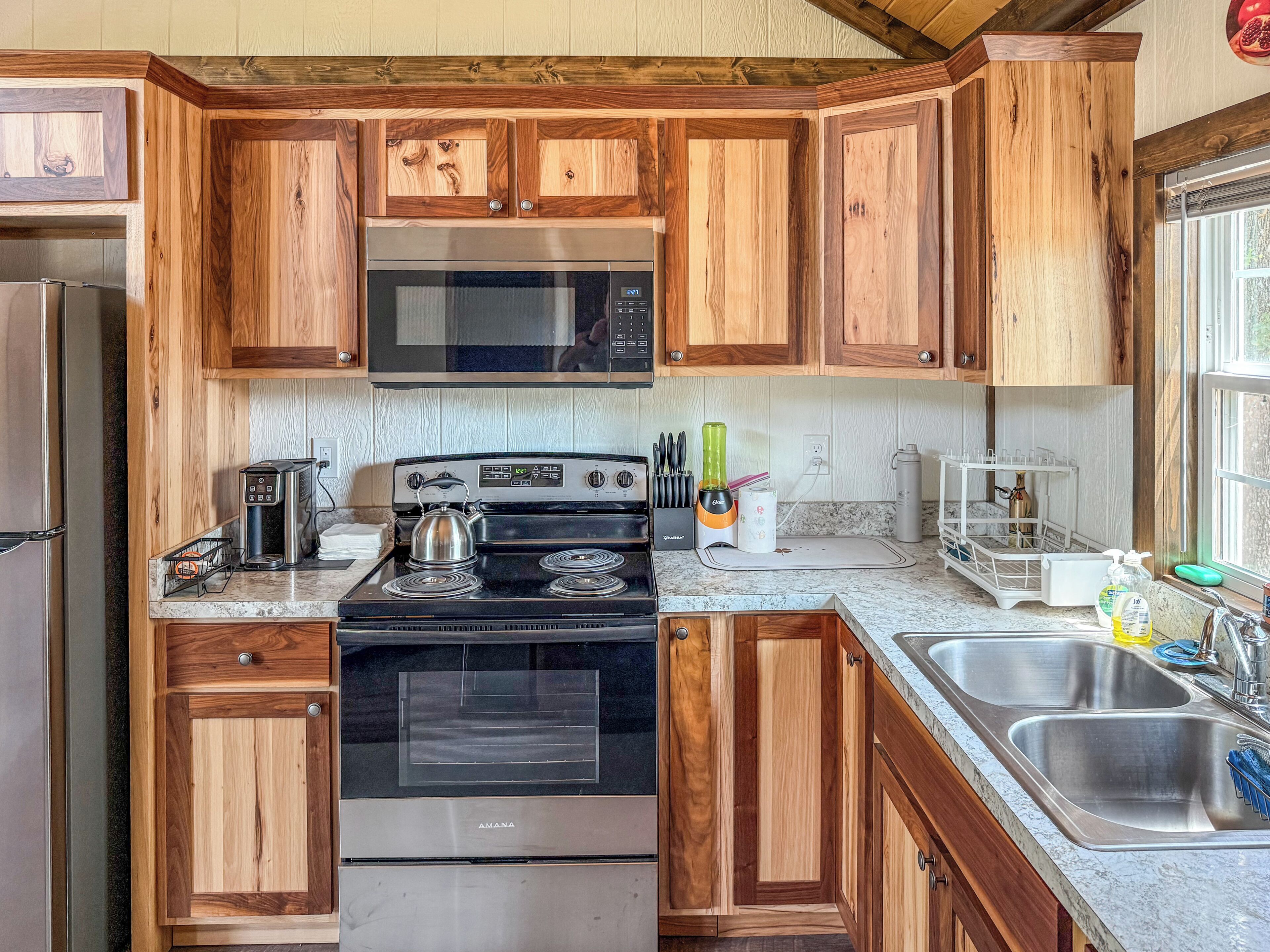 A kitchen with wooden cabinets, stainless steel appliances, and a window providing natural light.