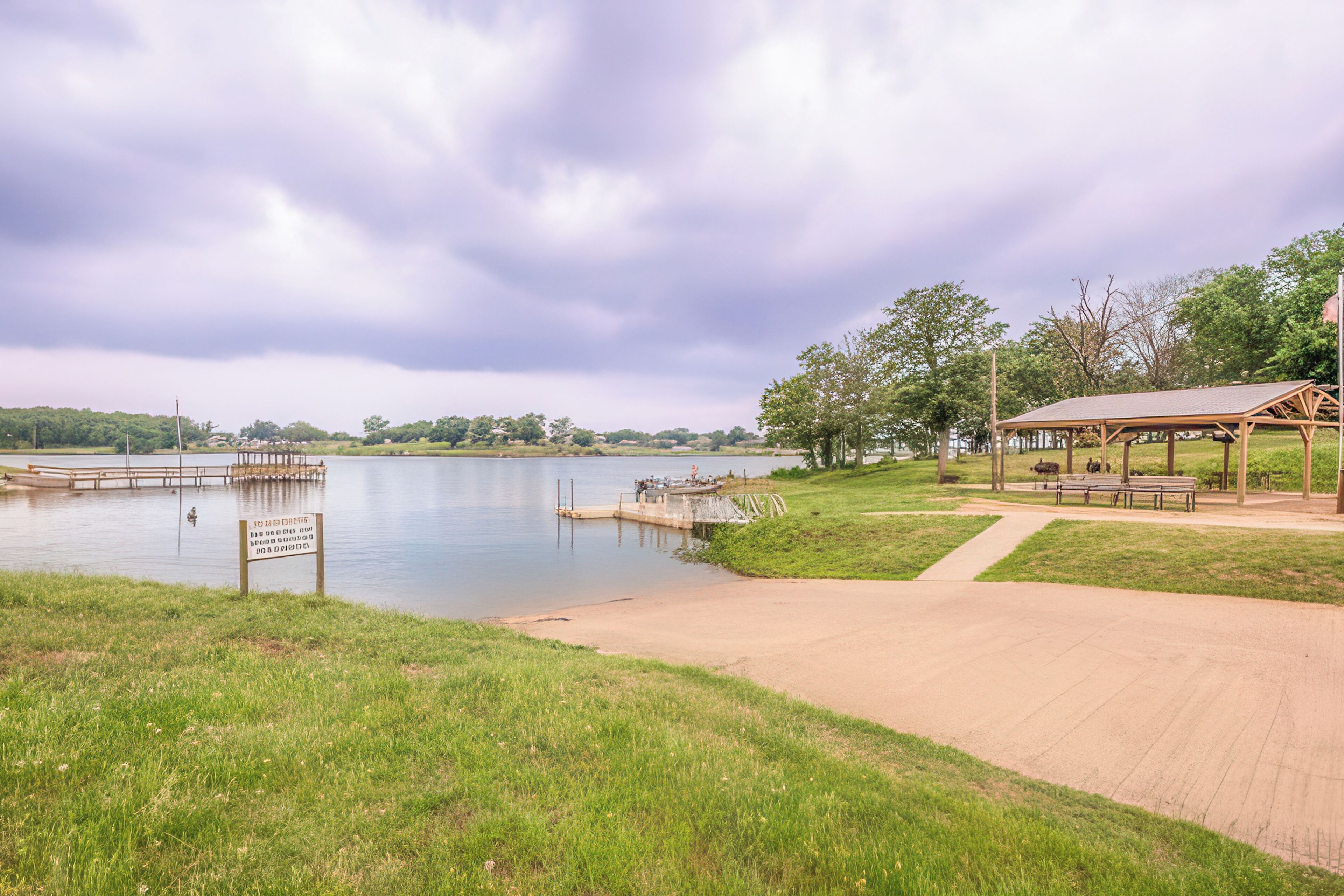 A lakeside park with a wooden dock, a gazebo, and a walking path.