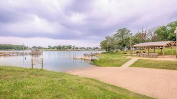 A lakeside park with a wooden dock, a gazebo, and a walking path.