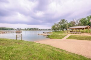Un parque junto al lago con un muelle de madera, un pabellón y un sendero para caminar.