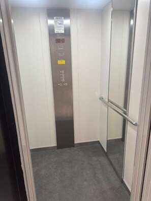 An elevator with a control panel, a handrail, and a door.