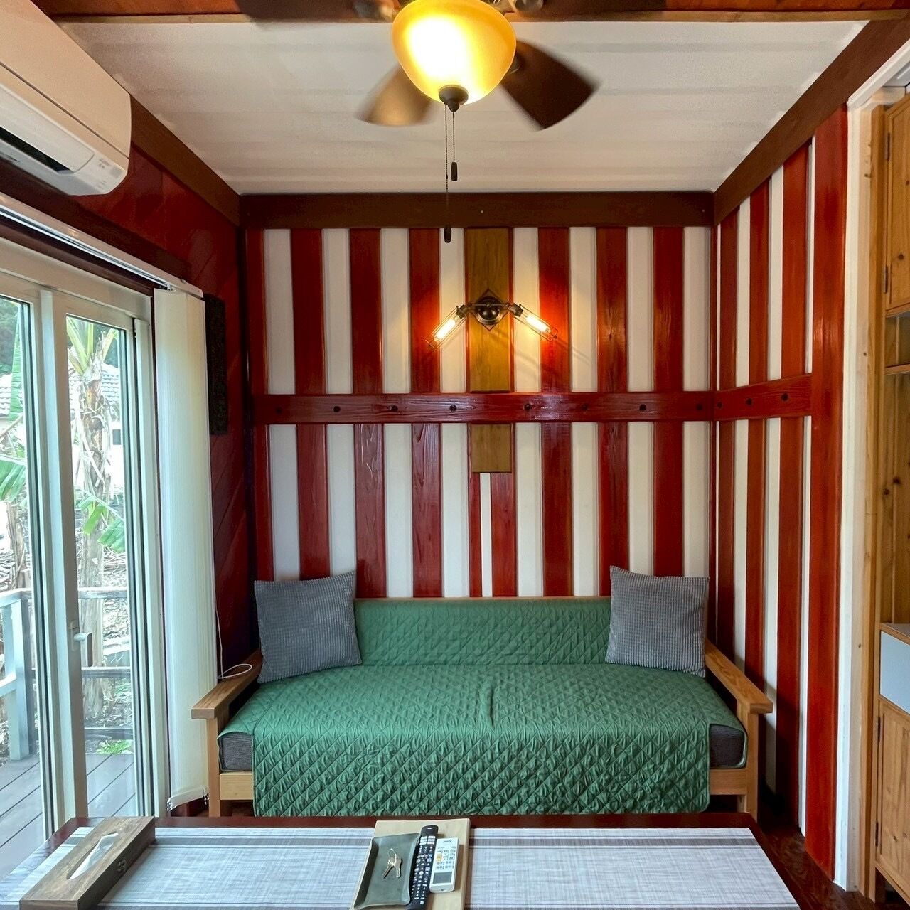 A room with a bed, a ceiling fan, and a window.