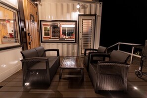 Une terrasse extérieure avec des meubles en osier, une table et un barbecue.