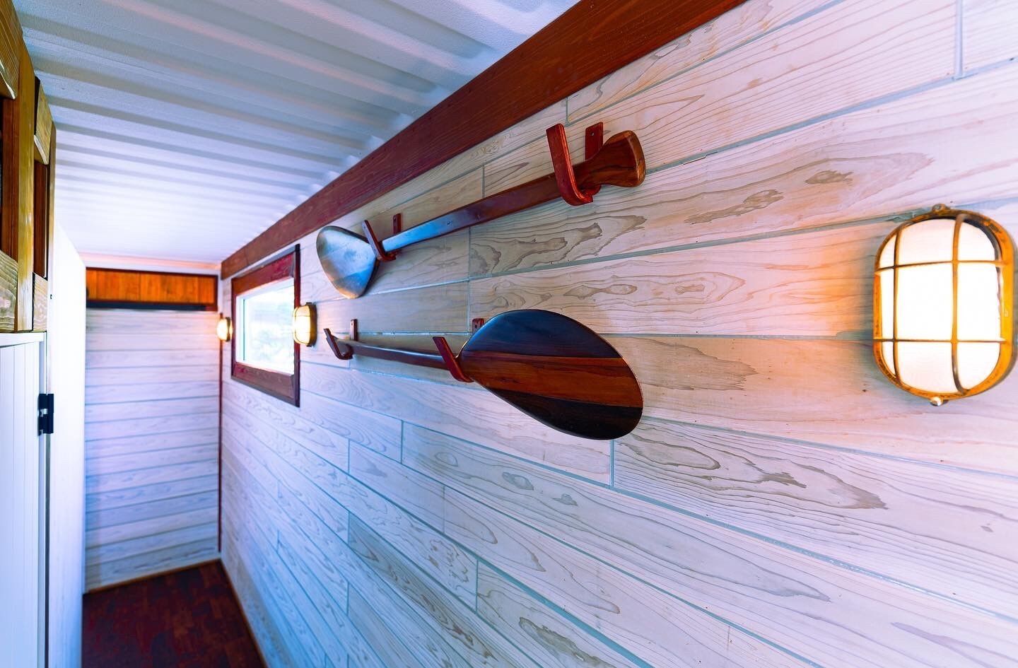 A hallway with wooden paneling, a wall-mounted light fixture, and a door with a handle.