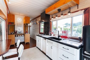Une cuisine moderne avec des meubles en bois, un plan de travail noir et une grande fenêtre donnant sur l’extérieur.