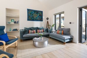 A modern living room with a sofa set, a coffee table, and a bookshelf. - An Mordros - sleeps 6 guests  in 3 bedrooms (Hayle)