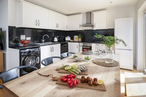 Eine moderne Küche mit weißen Schränken, einer schwarzen Arbeitsplatte und einem Holzespeisetisch, gedeckt mit Speisen und Getränken.