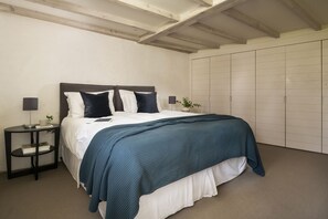 A bedroom with a bed, bedside tables, a wardrobe, and a ceiling with exposed beams. - Avallen Barn - sleeps 8 guests  in 4 bedrooms (Helford)