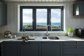 A kitchen with a large window overlooking a coastal landscape. - Blue Haze - sleeps 6 guests  in 3 bedrooms (Hayle)