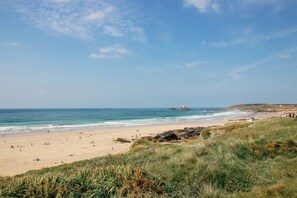 Ein Strand mit Personen, einem Felsen und blauem Himmel.