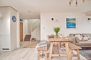 Ein modernes Wohnzimmer mit einem Holzesstisch, einer Couch und einer Treppe, die zu einer weiteren Ebene führt.