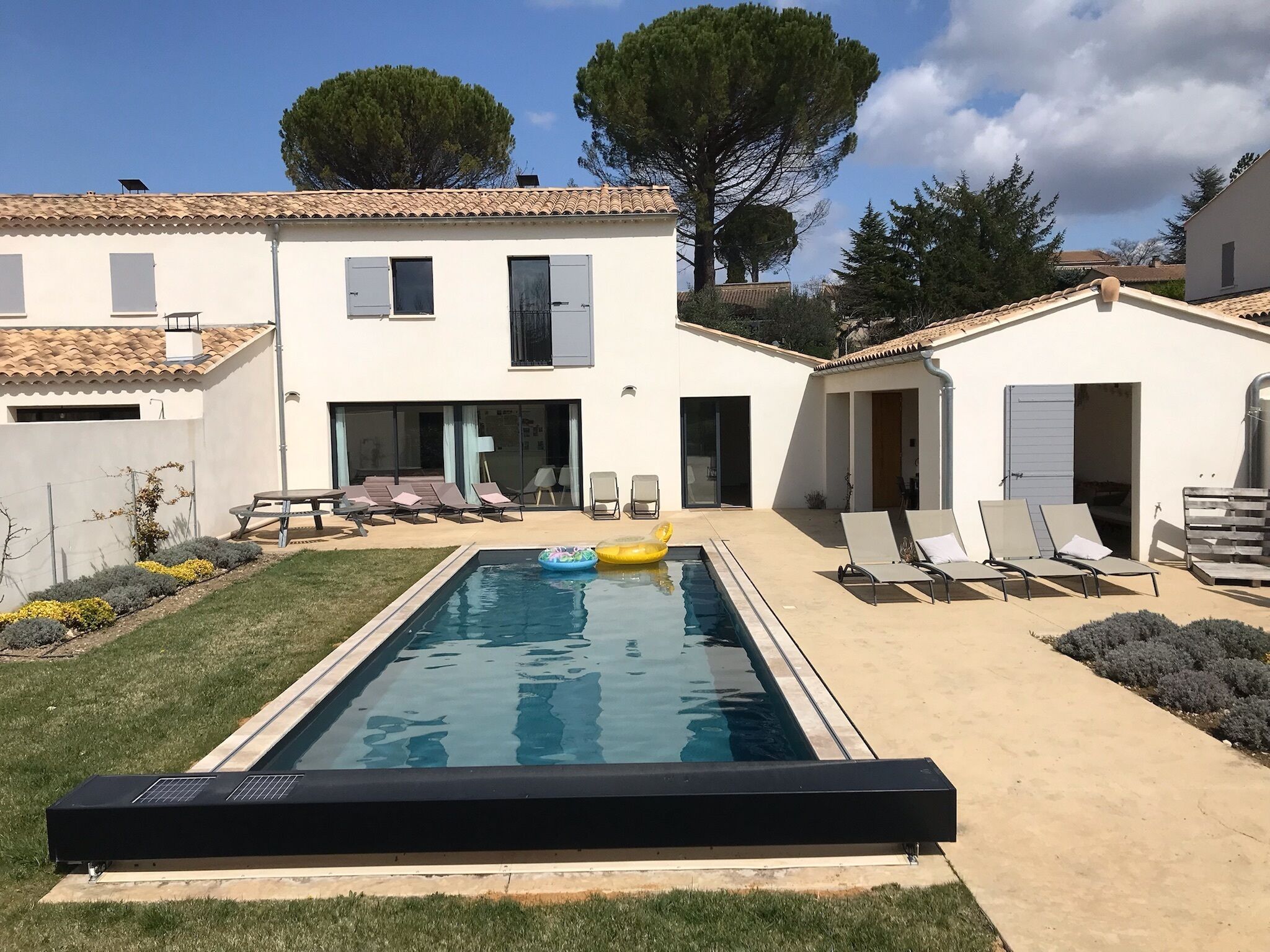 Une piscine avec des chaises longues et un espace patio couvert.