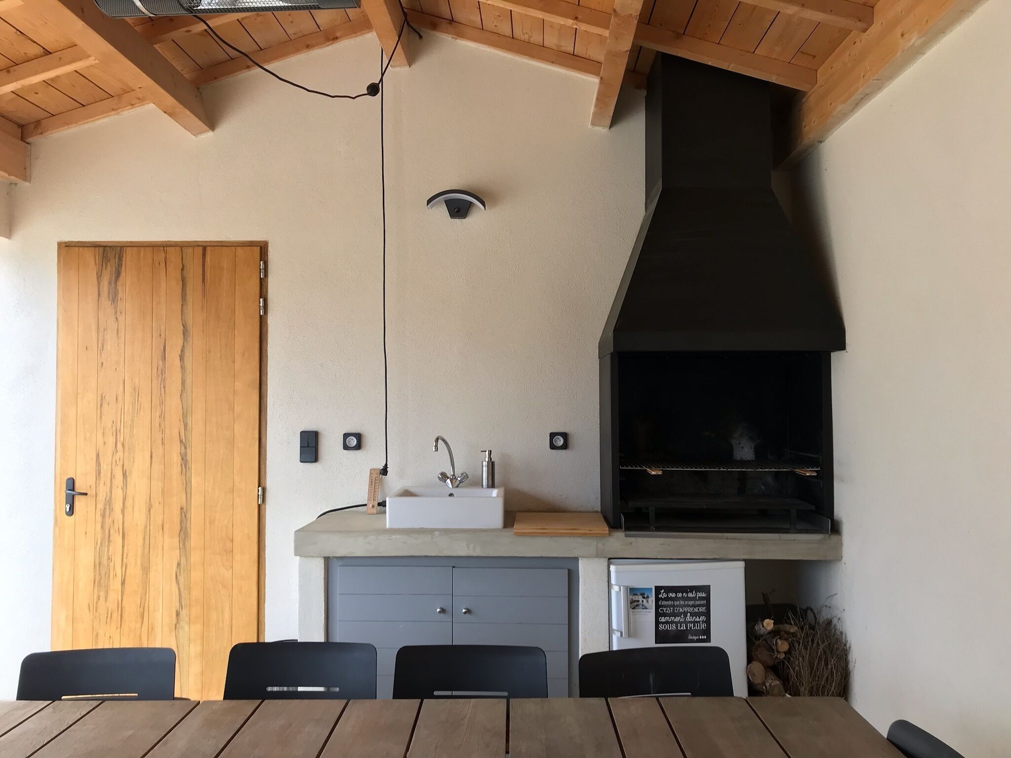Una cocina moderna con horno integrado, pileta y comedor con mesa y sillas.