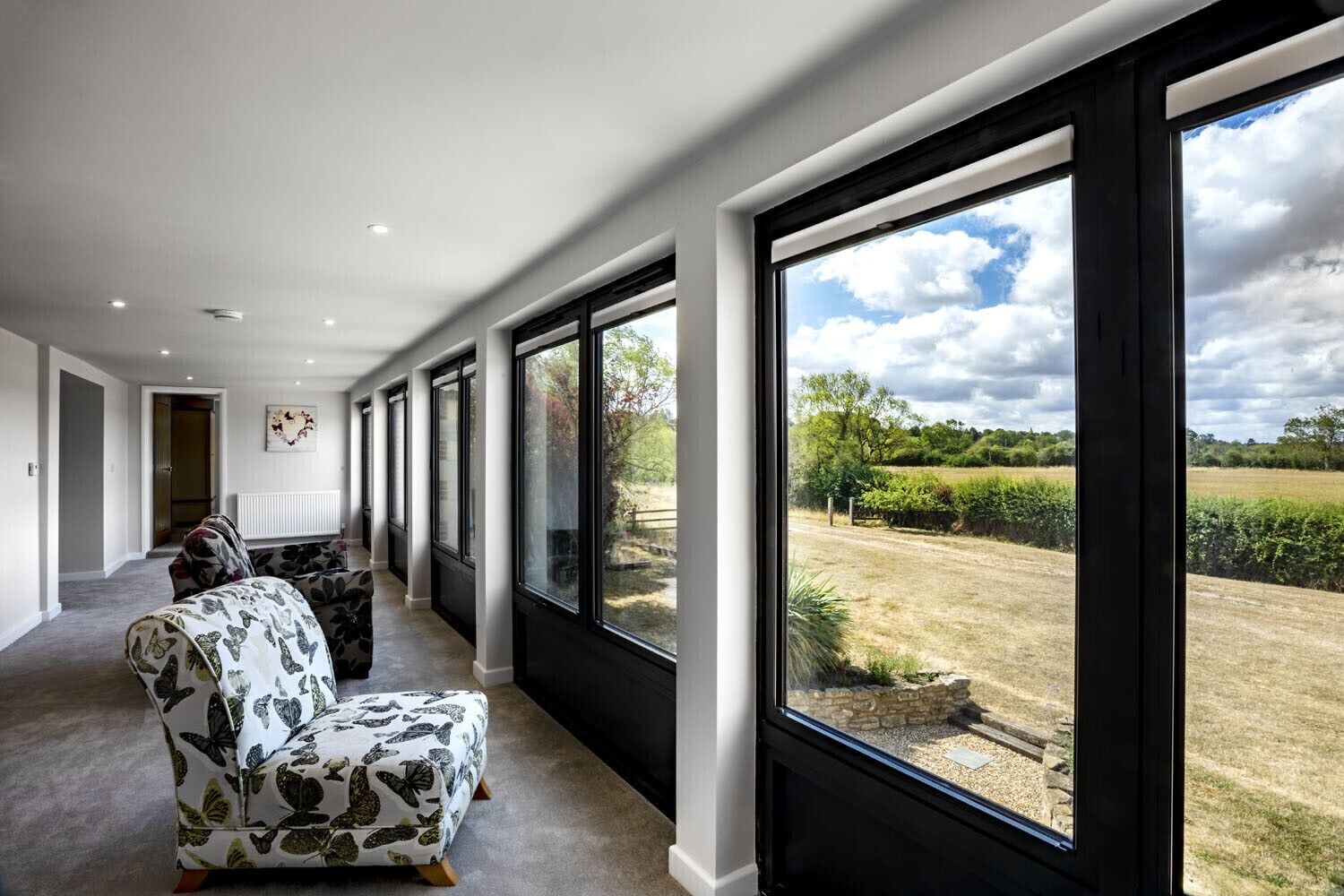 Un pasillo amplio con ventanas grandes, un sofá y una zona de comedor.