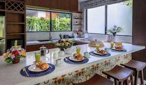 Een moderne keuken met een ontbijtarrangement, onder meer met croissants, fruit en een koffiehoek.