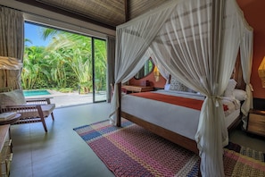 Ein Zimmer mit Bett, Schreibtisch und Blick auf Pool und Grünflächen.