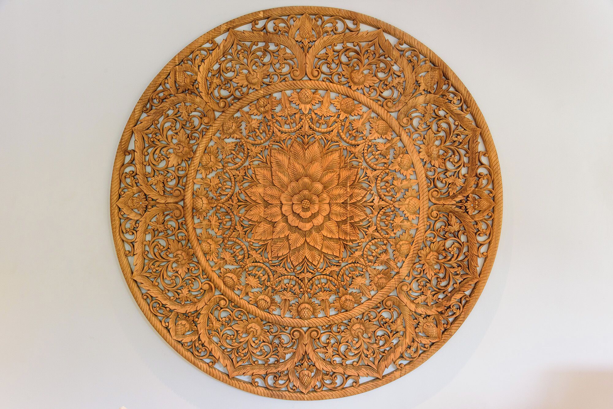 Un tapiz de madera circular con delicados diseños florales y geométricos.