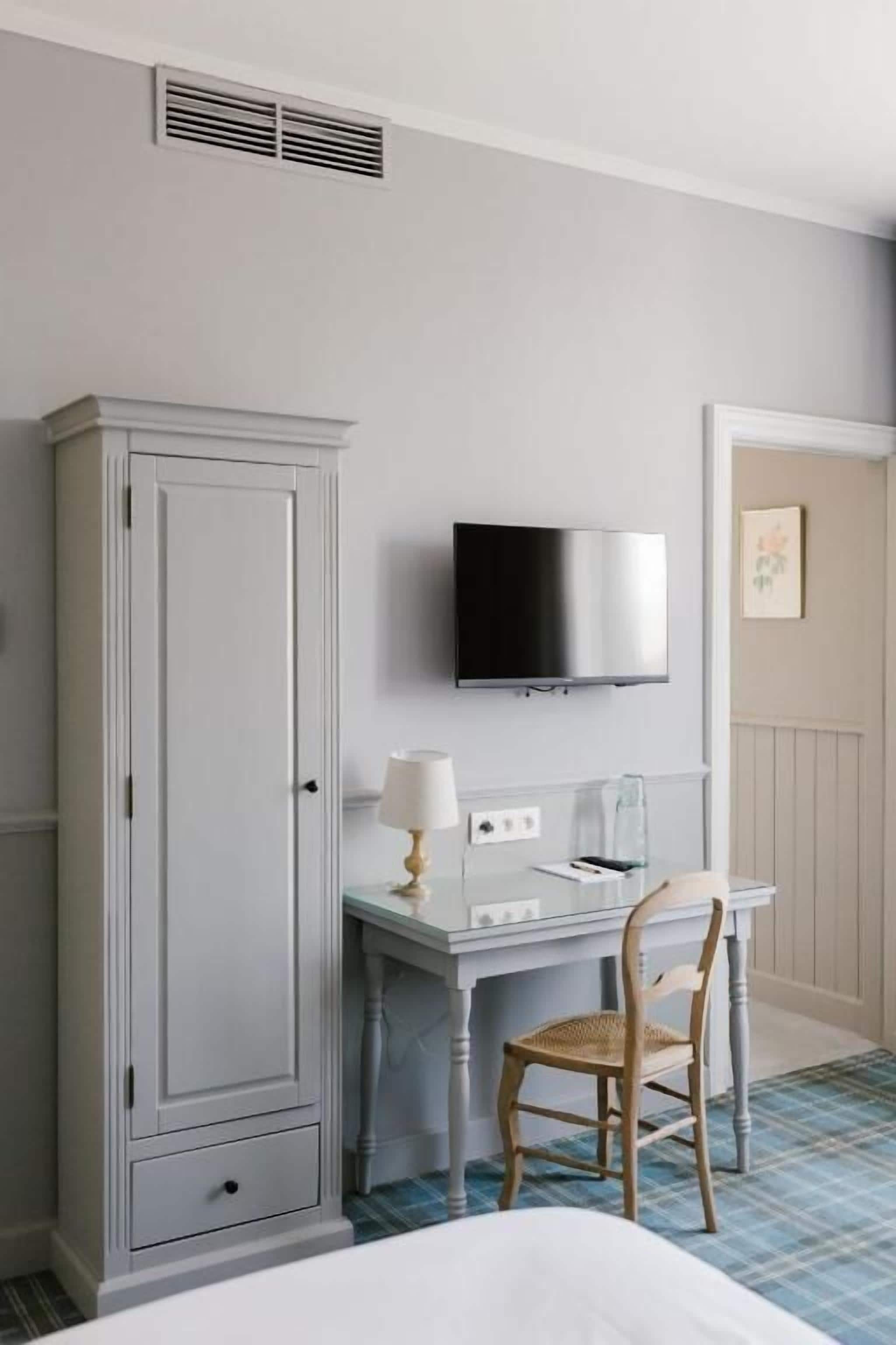 Een hotelkamer met een bed, een bureau met stoel, een televisie en een kledingkast.