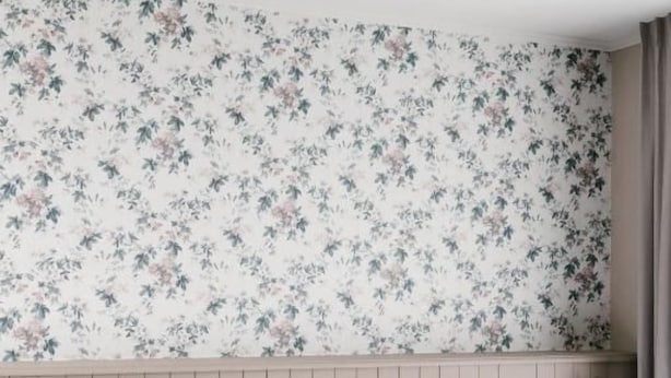 A hotel room with a bed, a nightstand, a lamp, and a floral wallpaper.