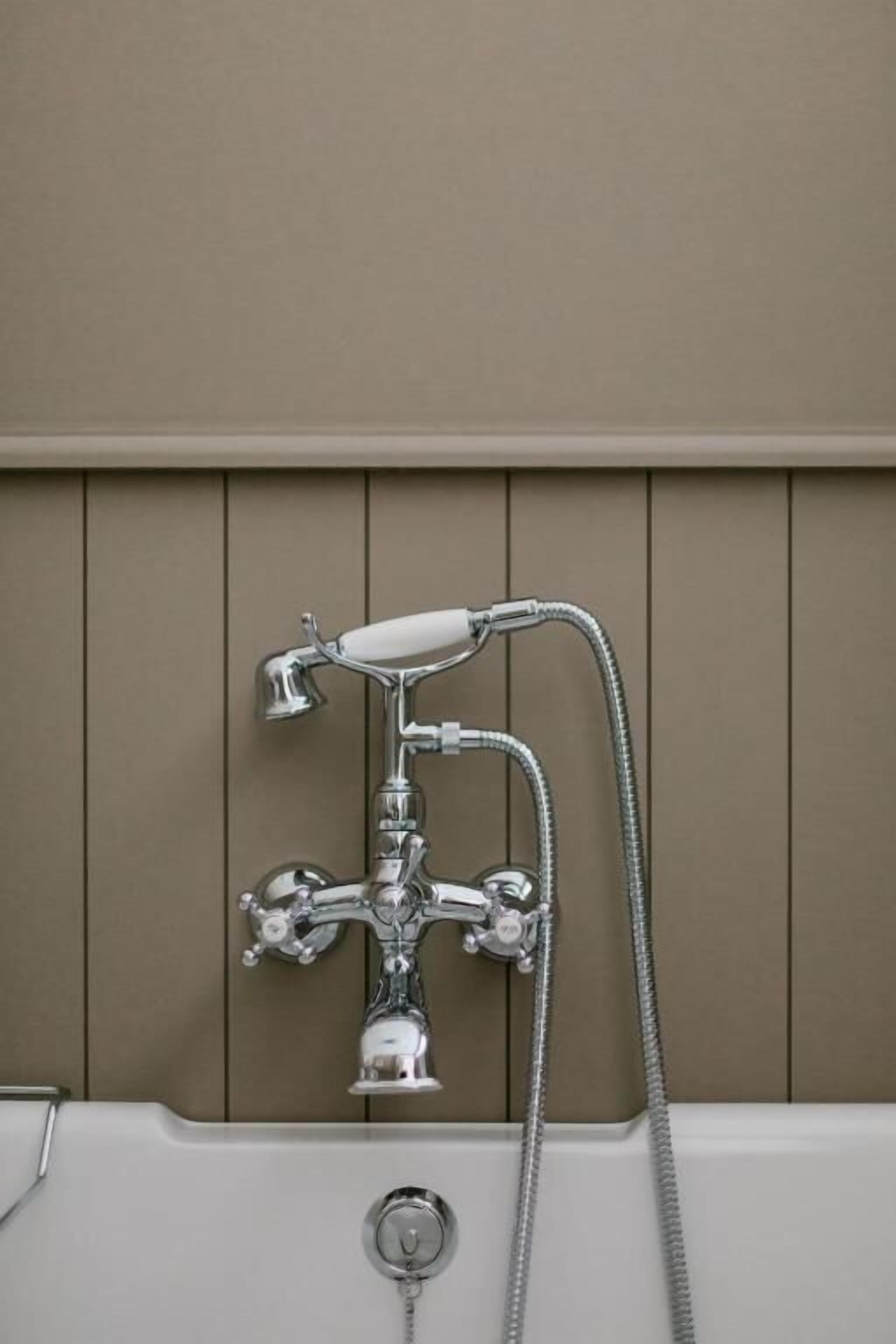 Een badkamer met een chromen douchekop, een handdouche en een wandmengkraan.