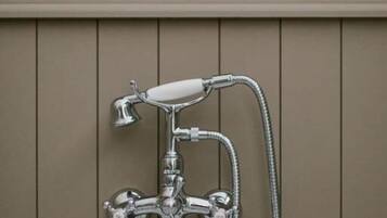 Een badkamer met een chromen douchekop, een handdouche en een wandmengkraan.