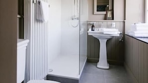 A bathroom with a toilet, shower, and sink.