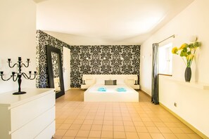 A modern bedroom with a large bed, a bedside table, a mirror, and a wall-mounted vase with flowers. - Stenen Mas 'Le Mas Toupian'; 500m², Mediterranean Garden, Tennis, Pool, Pétanque, Air Con (Goudargues)