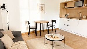 Una sala moderna con un sofá, una mesa de centro y un comedor con sillas y una pequeña mesa.