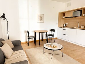 Ein modernes Wohnzimmer mit Sofa, Couchtisch und Essbereich mit Stühlen und einem kleinen Tisch.