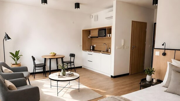 Habitación de hotel moderna con cama, sofá, mesa de comedor y kitchenette.