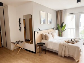 Ein Schlafzimmer mit einem Bett, einem Spiegel, einem kleinen Tisch und einer Pflanze.