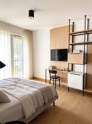 Une chambre d’hôtel équipée d’un lit, d’un bureau, d’une chaise, d’une télévision et d’une bibliothèque.