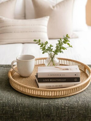 A wicker tray with a white mug, a stack of books, and a small vase with green leaves on a textured fabric surface. - Old Town Heart – National Stadium Tower 26 (Warsaw)