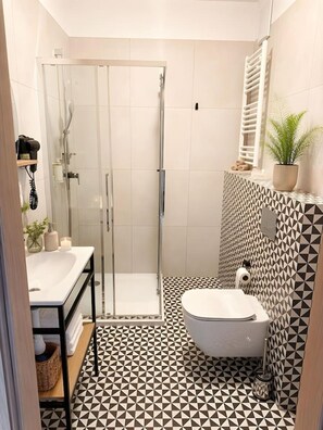 A bathroom with a glass-enclosed shower, a toilet, and a sink with a towel rack. - Old Town Heart – National Stadium Tower 26 (Warsaw)