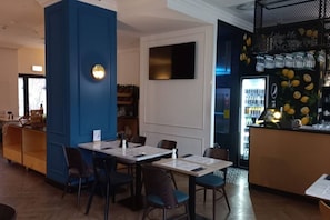 A restaurant interior with tables, chairs, a bar area, and a refrigerator stocked with beverages. - Old Town Heart - National Stadium Tower 87 (Warsaw)
