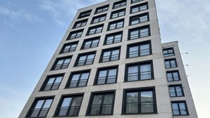 Ein mehrgeschossiges Gebäude mit moderner Architektur, das eine Reihe von Balkonen und großen Fenstern aufweist.