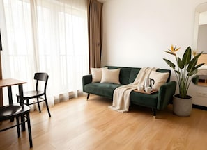 A living room with a green sofa, a coffee table, and a potted plant. - Old Town Heart - National Stadium Tower 47 (Warsaw)