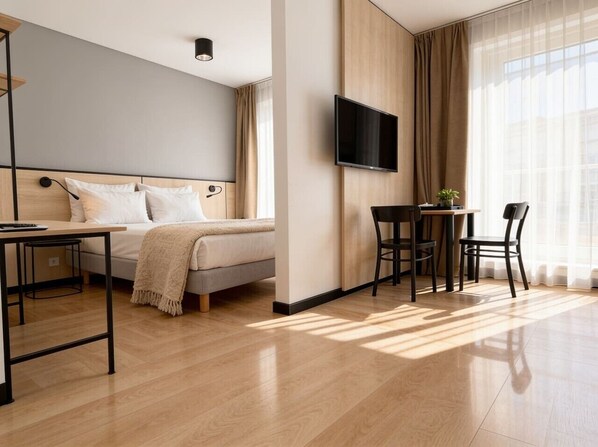 Una habitación de hotel moderna con cama, escritorio, televisor y zona de comedor.