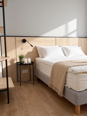 A bedroom with a bed, bedside table, lamp, and a small potted plant. - Old Town Heart - National Stadium Tower 47 (Warsaw)