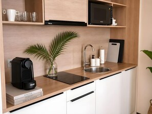 A modern kitchen with a built-in microwave, a kettle, a sink, and a coffee machine. - Old Town Heart - National Stadium Tower 22 (Warsaw)