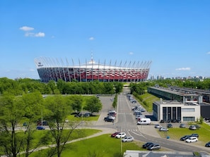 Ein Stadion mit markanter Dachkonstruktion, umgeben von Parkplätzen und Grünflächen.