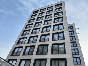Ein mehrgeschossiges Gebäude im modernen Architekturstil, mit mehreren Balkonen und großen Fenstern.