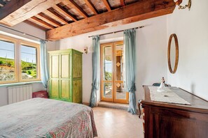 Une chambre à coucher comprenant un lit, une armoire en bois, une commode, un miroir et une vue sur l’extérieur.